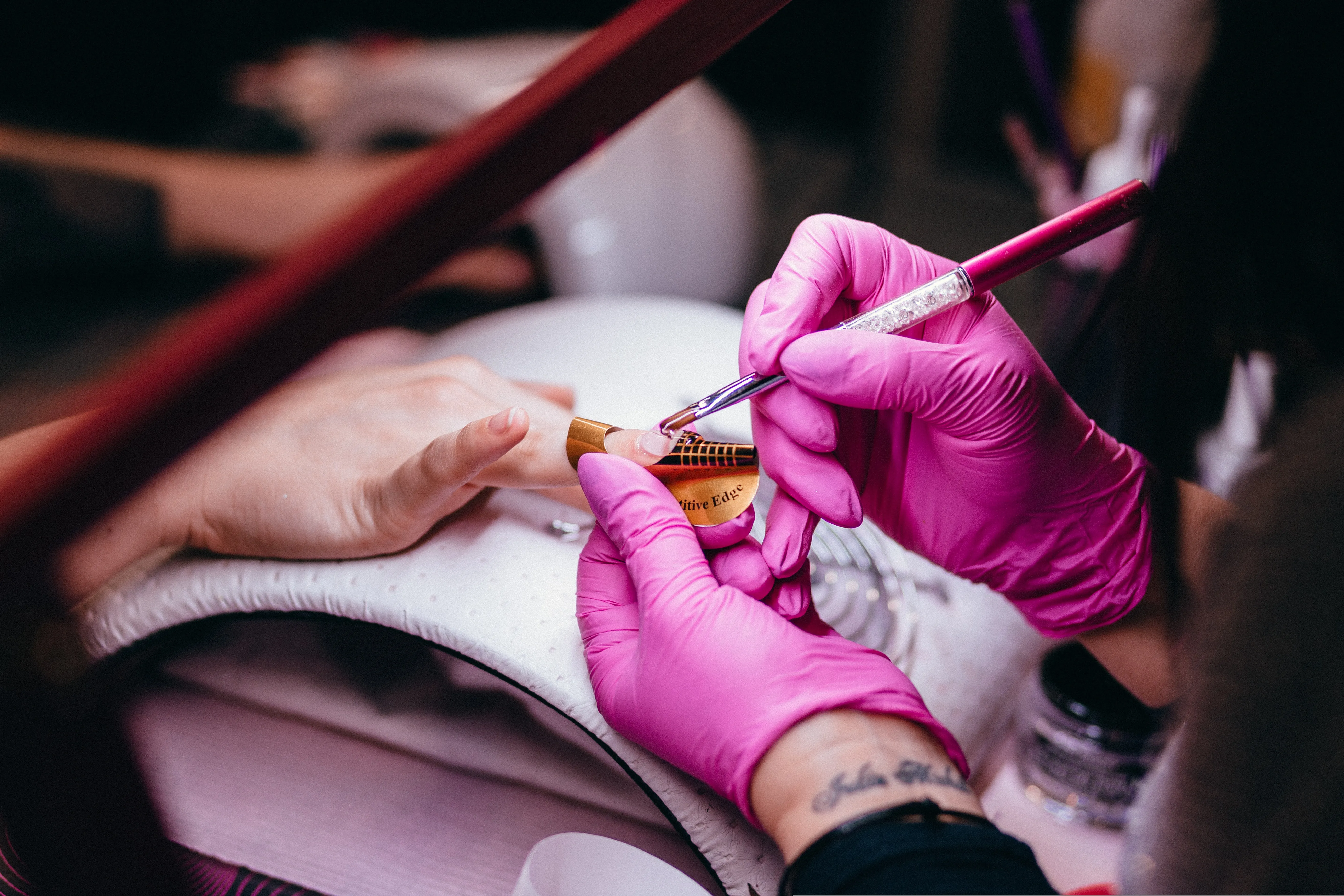 Prothésiste ongulaire travaillant les ongles d'une cliente sous la lampe, salon de Roanne